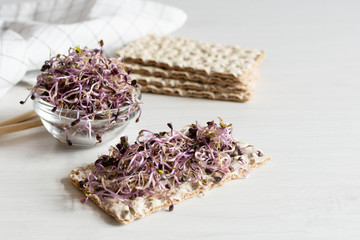 Crispbread with red cabbage sprouts on white wooden table. Sprouted seeds. Detoxification.