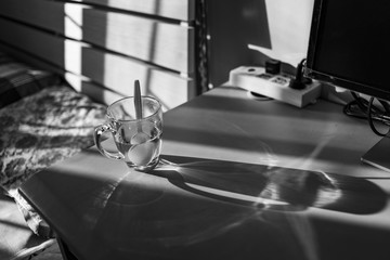 the half-full glass mug on the desk in a study room, monochrome