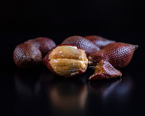 Snake fruit salak whole and one in section on black background. Exotic fruit. HLS. Selective focus. Сloseup.