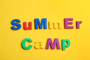 Phrase SUMMER CAMP made with magnet letters on yellow background, flat lay