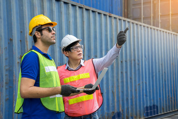 Warehouse laborer with engineer wearing a hardhat unloading works with forklift loader at the...