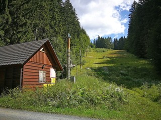 Ski slope overgrown with grass in summer, with ski lift and cottage