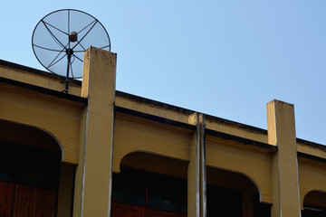 Old satellite dish on yellow building