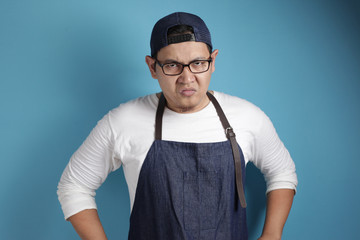 Photo image of funny Asian male chef or waiter shows cynical unhappy angry facial expression