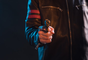 The hand presses the trigger of the gun and the flame from the shot escapes from its muzzle
