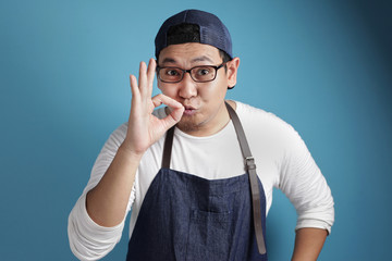 Portrait of happy smiling Asian chef or waiter shows OK delicious hand gesture