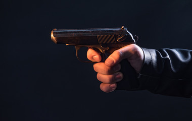 The hand presses the trigger of the gun and the flame from the shot escapes from its muzzle
