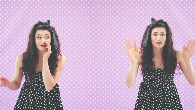 Adorable young twin sisters in black polka-dots dresses, leaning to the camera, whispering, behaving comically.