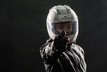 A bandit in a motorcycle helmet and leather jacket with a gun