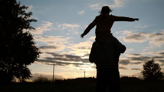 Father and child play pilots. A field with a sunset. Slow motion.