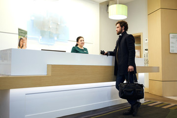 young attractive bearded man cheking in the hotel. side view photo. discounts, sale, guy choosing a room