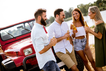 Obraz premium Group of young people drinking and having fun by car outdoor