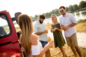 Group of young people drinking and having fun by car outdoor