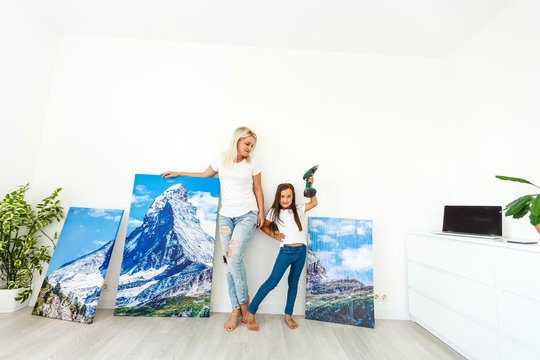 woman hangs photo canvas on wall