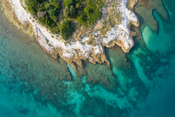 A fragment of an uneven coastline surrounded by a sea of turquoise water. Shooting from a drone.