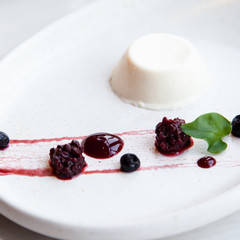 Panna cotta dessert with berries on a white plate