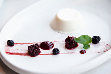 Panna cotta dessert with berries on a white plate