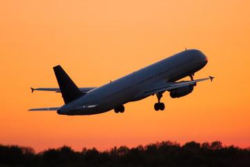 Fototapeta na wymiar Startendes Flugzeug fliegt dem Sonnenuntergang entgegen