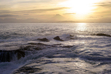 Fuji Mountain Landscape and Breaking Wave over Reef Rock Before Sunset                         
