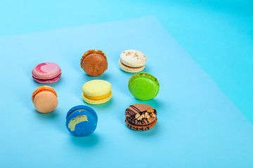 Different types of colorful sweet macaroons dessert on blue background