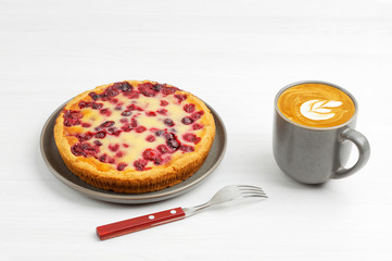 Homemade berry pie with yogurt filling and cup of coffee cappuccino on white wooden table