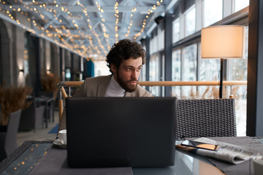 serrious guy cannot solve some problems, watching passers-by who is walking on the street. close upphoto. guy sitting behind the laptop