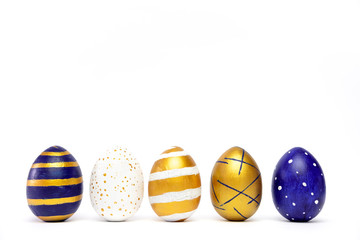 Five easter eggs trendy colored classic blue, white and golden decorated on white table. Happy Easter card with copy space for text. Minimal style.