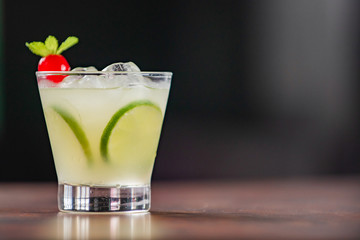 Lemon caipirinha, decorated with cherry on a wooden table