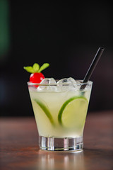 Lemon caipirinha, decorated with cherry on a wooden table