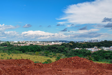 Fototapeta na wymiar Horizonte com pilha de terra, floresta cidade e céu azul