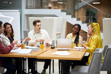 young start up team spending great time in the office, pleasant girl with yellow dreads telling jokes to her frineds, close up photo. good relationship among co-workers