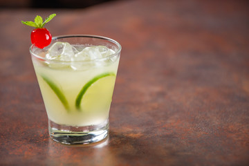 Lemon caipirinha, decorated with cherry on a wooden table