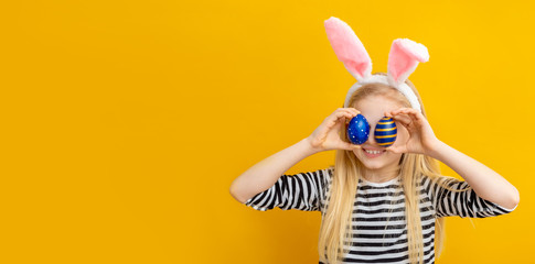 Easter banner with copyspace. Girl in rabbit bunny ears on head on yellow studio background....