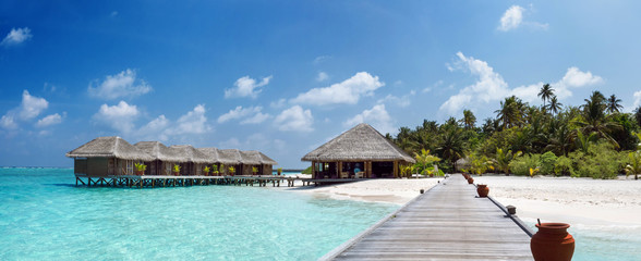 Tropical Island with Palm Trees and Wooden Pier in Indian Ocean on Maldives.