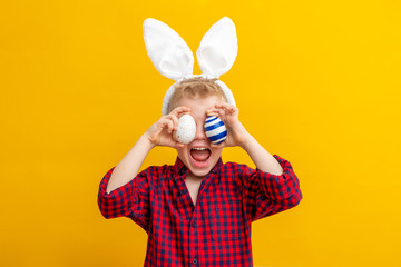 Excited boy in rabbit bunny ears on head on yellow studio background. Cheerful crazy smiling happy...