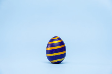 Happy Easter. One easter egg trendy colored classic blue, white and golden on blue background. Copy space. Minimal style