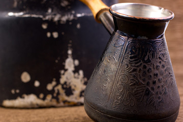 Cezve copper coffee maker with wooden handle for making coffee on an open fire. Background for the menu of restaurants, coffee houses and publications about coffee.