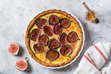 Homemade quiche tart with figs, cream cheese and honey on light wooden background. Vintage style. Top view.