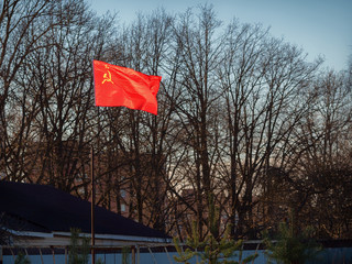 The red Soviet flag glows brightly in the sun on the suburban area behind the fence