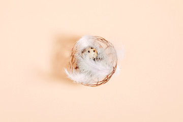 Quail eggs pattern, collection of quail eggs with feathers on beige background. Easter concept. Flat lay, top view, copy space