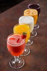 bowls of natural juices, passion fruit, grape, strawberry, orange, pineapple, on a table with dark background