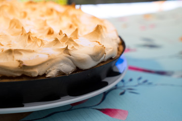 A cake with meringue frosting on a plate on a decorative set table outdoors close up