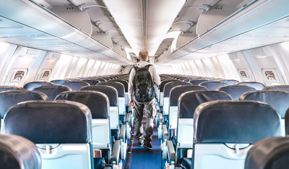 Inside view of commercial airplane with lonely man traveler - Emergency travel concept about flight cancellation - Aerospace industry crisis with empty plane on bright azure filter