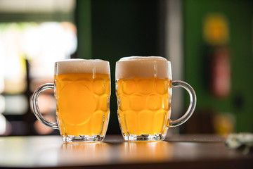 two mugs full of chopp, with chopp pilsen on a rustic table
