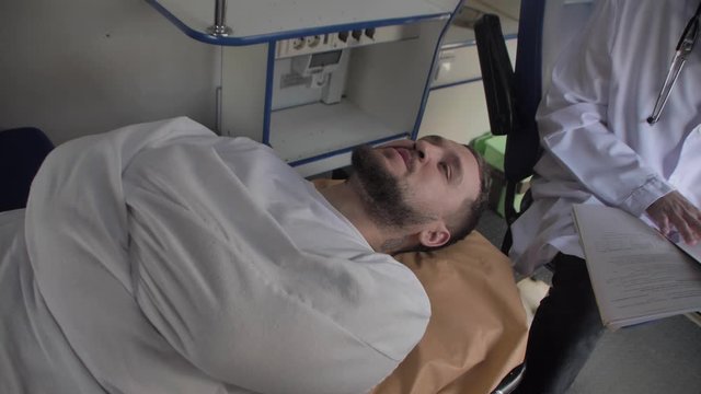 Psycho lies on the couch in the ambulance, the doctor tries to find out the cause of his illness