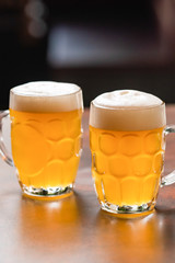 two mugs full of chopp, with chopp pilsen on a rustic table