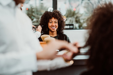 Beautiful latin woman with short curly brown hair getting a treat at the hairdresser. Latin...