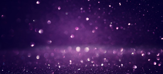 background of abstract glitter lights. black and purple. de focused