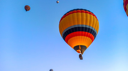 Colorful hot air balloons flying over the valley with fairy chimneys in winter season. Lots of Hot air balloons at the sunrise sky landscape in Cappadocia, Turkey