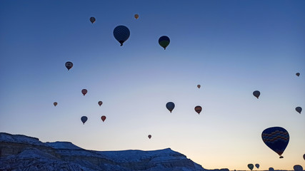 Colorful hot air balloons flying over the valley with fairy chimneys in winter season. Lots of Hot air balloons at the sunrise sky landscape in Cappadocia, Turkey
